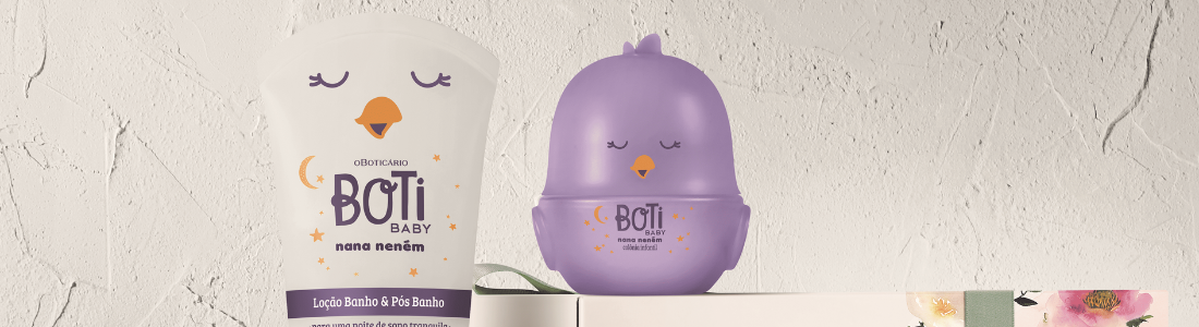 Sobre uma superfície clara texturizada, um conjunto de produtos Boti Baby se apresenta. À esquerda, um tubo branco e roxo de loção com um desenho de lua crescente e estrelas. Ao centro, um recipiente roxo em formato de pintinho com olhos fechados. À direita, duas caixas brancas da O Boticário, uma delas adornada com uma faixa de papel floral. A composição sugere um presente delicado e voltado para cuidados infantis.