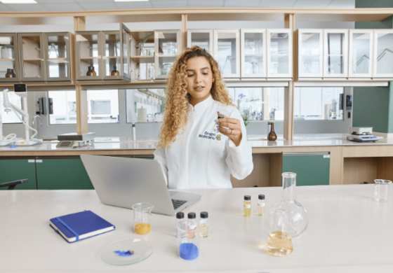 Mulher em laboratório do Grupo Boticário segurando frasco com fragrância.