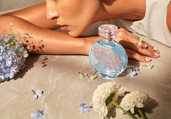 Blue perfume bottle with gold floral patterns on marble.