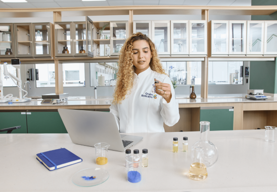 Scientist in a white lab coat holding a small vial in a modern laboratory.
