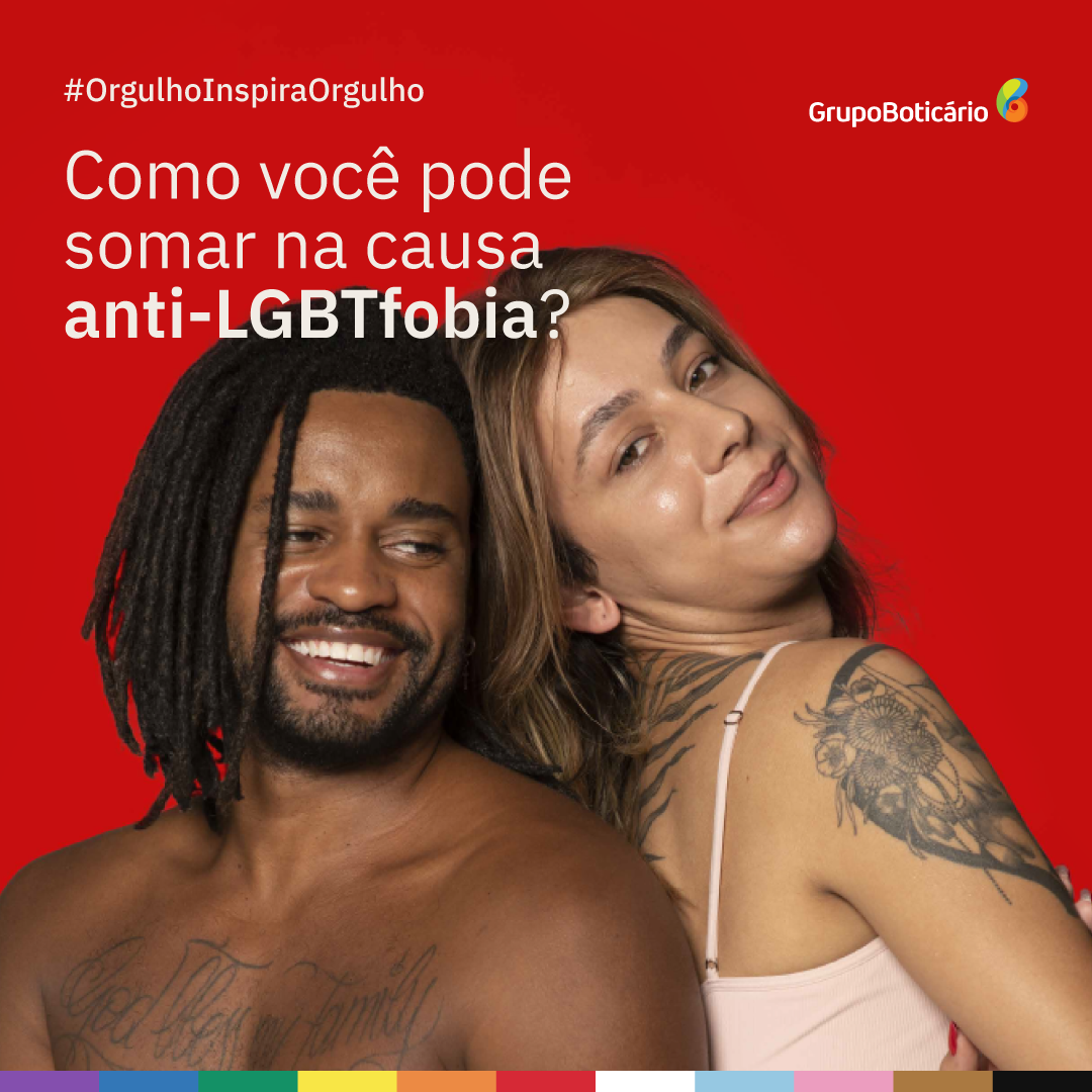 Foto Letramento Anti-LGBTFobia. Na imagem com fundo vermelho, do lado esquerdo escrito #OrgulhoInspiraOrgulho Como você pode somar na causa anti-LGBTfobia? Do lado direito temos o logo Grupo Boticário. Ao centro, temos um homem negro com dreads e uma mulher branca com tatuagens