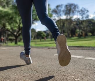 imagem vista do chão dos tênis de uma pessoa correndo em parque