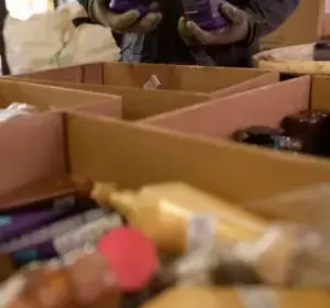 Imagem de embalagens vazias coletadas. No fundo, tem uma pessoa segurando embalagens nas mãos