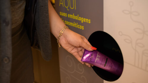 Imagem de uma pessoa descartando a embalagem de shampoo no lugar correto. A foto ilustra a matéria sobre o Edital Extinto, do Grupo Boticário, para apoiar iniciativas relacionadas à economia circular.
