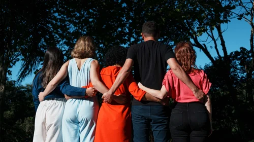 Cinco pessoas abraçadas, de costas, em uma área externa. São quatro mulheres e um homem. A imagem representa a atualização dos Compromissos para o Futuro do Grupo Boticário, publicados em seu 12º Relatório ESG.