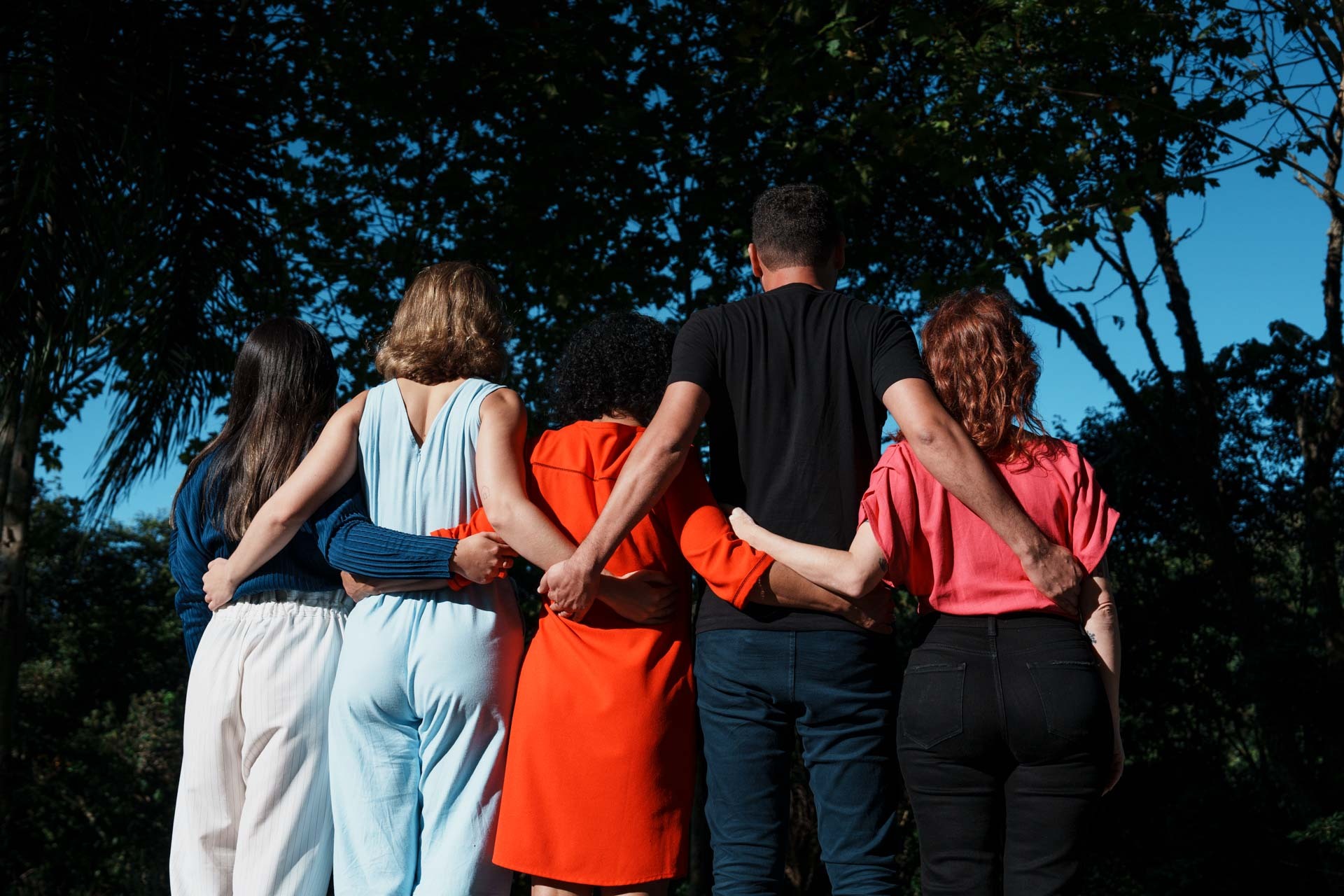 Cinco pessoas abraçadas, de costas, em uma área externa. São quatro mulheres e um homem. A imagem representa a atualização dos Compromissos para o Futuro do Grupo Boticário, publicados em seu 12º Relatório ESG.