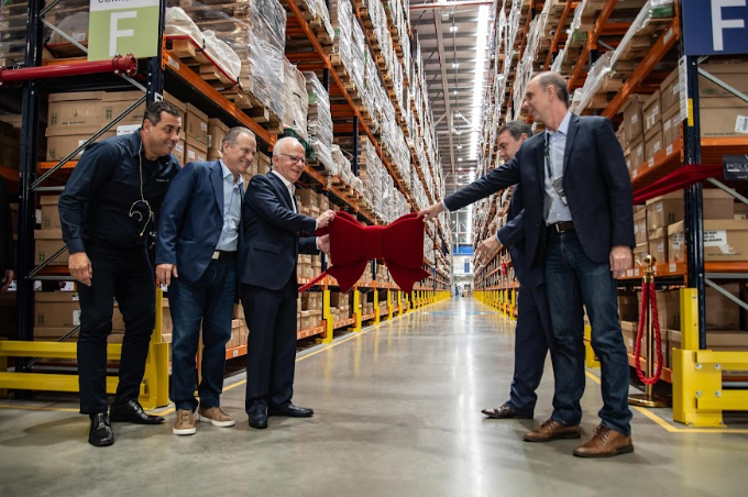 Imagens de cinco homens de terno segurando um laço vermelho para inaugurar o novo centro de distribuição do Grupo Boticário em Cajamar, em São Paulo.