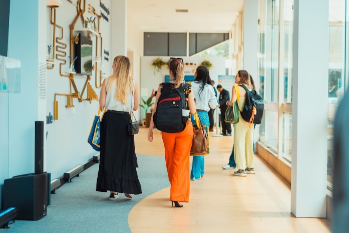 Imagem de quatro mulheres de costas, caminhando no corredor imersivo do Grupo Boticário no Congresso de Cosmetologia, IFSCC.