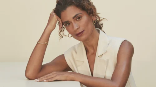 Mulher sentada e com a mão apoiada sob bancada.