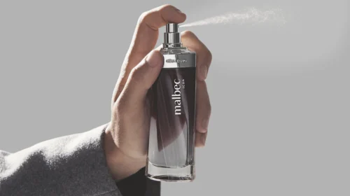 homem segurando perfume malbec que está sendo espirrado.