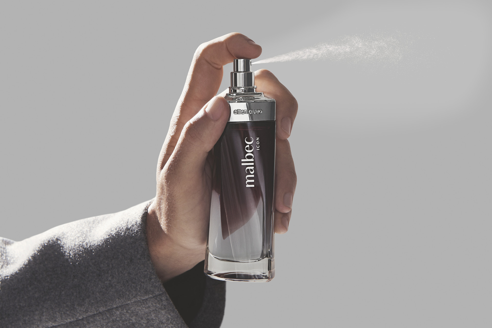 homem segurando perfume malbec que está sendo espirrado.