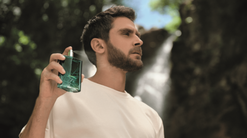 Homem em cachoeira segurando o perfume Arbo.