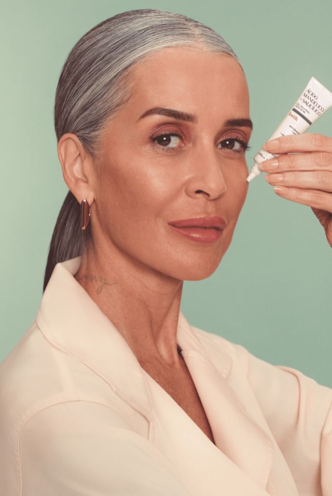 Mulher de cabelos grisalhos segurando um produto Botik com "Ácido Mandélico Salicílico".