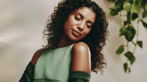 Mulher de olhos fechados apreciando um aroma, em clima de tranquilidade e bem-estar.