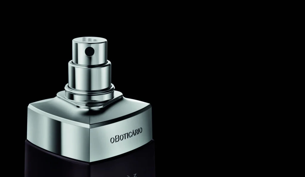 Uma fotografia destaca a parte superior de um frasco de perfume masculino com a marca "O Boticário" gravada.