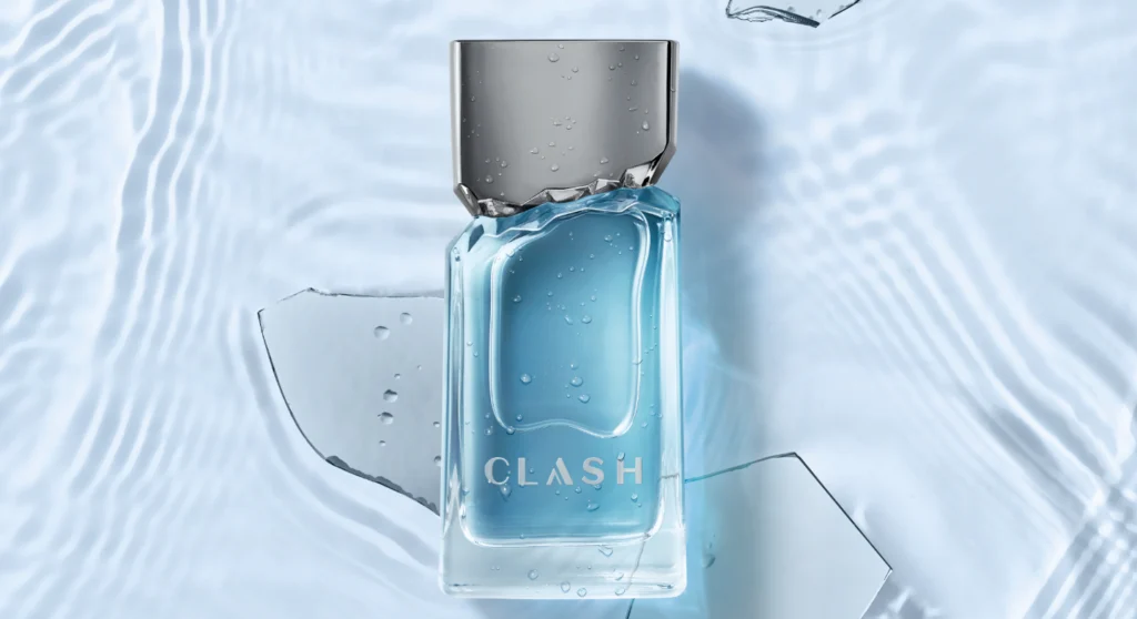 Frasco retangular de perfume "Clash" (líquido azul-celeste) em vidro transparente sobre fundo azul-claro, simulando água em movimento.